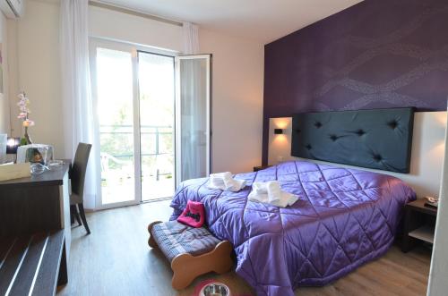 una camera con un letto viola e una grande finestra di Hotel Gambrinus a Lignano Sabbiadoro