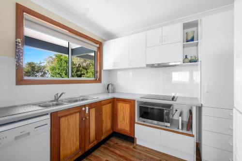 a kitchen with white cabinets and a window at Aqua Vincentia - Belle Escapes Jervis Bay in Vincentia