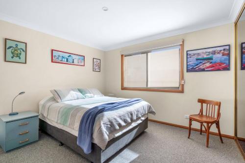 a bedroom with a bed and a chair and a window at Aqua Vincentia - Belle Escapes Jervis Bay in Vincentia