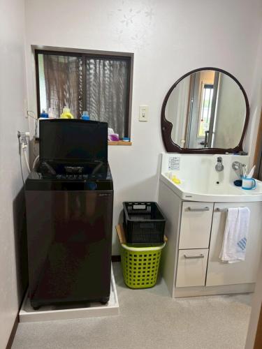 a bathroom with a sink and a dishwasher and a mirror at 木の家ゲストハウス松山ドミトリー館 in Matsuyama