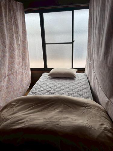 a bed in a room with a large window at 木の家ゲストハウス松山ドミトリー館 in Matsuyama
