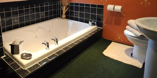 een badkamer met een bad, een toilet en een wastafel bij The Old Priory B&B in Bognor Regis