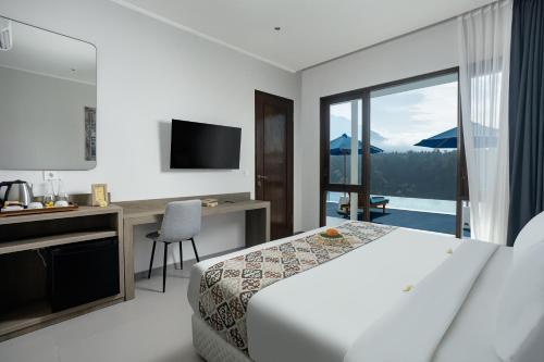 a hotel room with a bed and a desk and a window at Tapa Agung View Besakih in Menanga