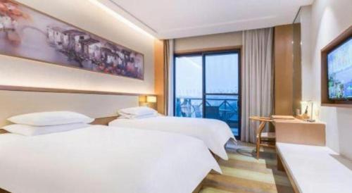 a hotel room with two beds and a large window at Deefly Yinrun Town Hotel in Deqing