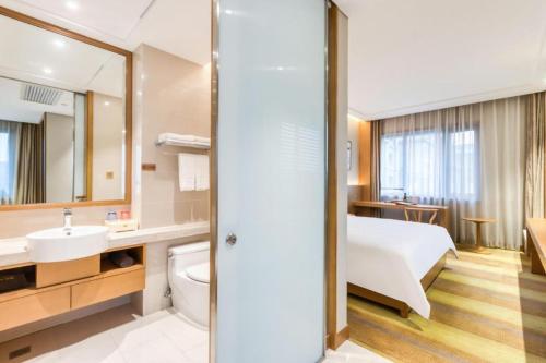 a bathroom with a bed a sink and a mirror at Deefly Yinrun Town Hotel in Deqing