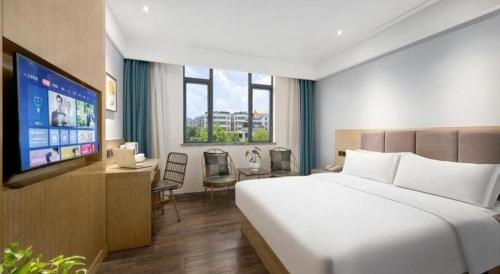 a hotel room with a bed and a television at Borrman Hotel Huizhou West Lake Shuidong Street in Huizhou