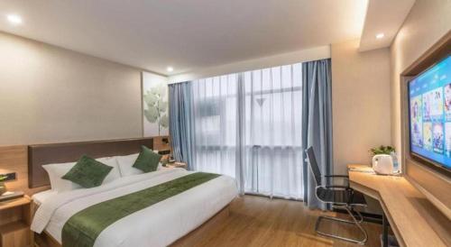 a hotel room with a large bed and a flat screen tv at GreenTree Inn Express Zhangjiagang Hexing Town Shazhou Professional Institue of Technology in Qiwei