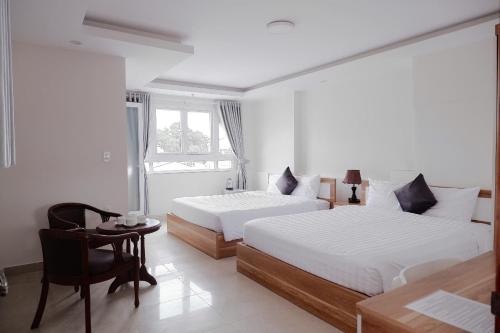 a hotel room with two beds and a chair at An Nam Paradise Dalat in Da Lat