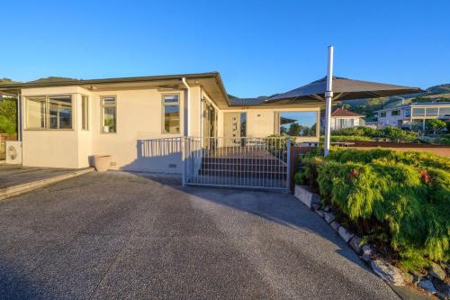 a house with a gate in front of a driveway at Sea Views and Sunsets in Nelson in Nelson