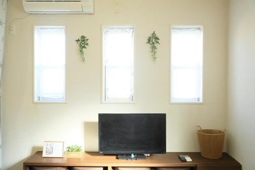 a television sitting on a table with three windows at Nao house in Takaishi