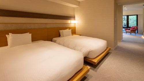 two beds in a room with a room with a chair at Riverte Kyoto Kamogawa in Kyoto