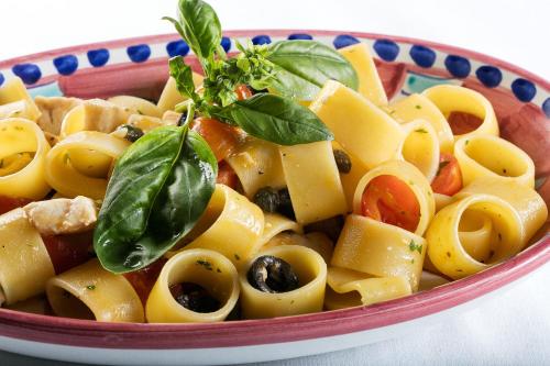 a bowl of pasta with a sprig of basil on top at Hotel Syrene in Capri