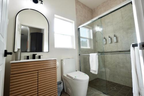 a bathroom with a toilet and a glass shower at Villa Fiorō -Bold Luxury 2BR - River & Coastal Vibe in Cocoa Beach