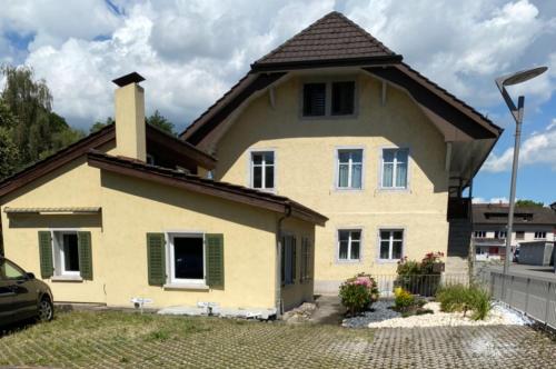 a large yellow house with a roof at Aabach Stay in Niederlenz