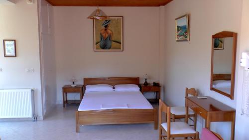 1 dormitorio con cama, mesa y espejo en Captain's Apartments, en Kiónion