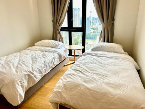 two beds in a room with a window at KL Central 31st floor KLCC view in Kuala Lumpur