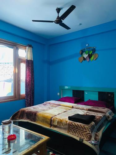 a blue bedroom with a bed with a ceiling fan at Trippy Homestay in Kasol