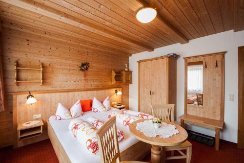 um quarto com uma cama e uma mesa num quarto em Gästehaus Alpenblick em Berwang