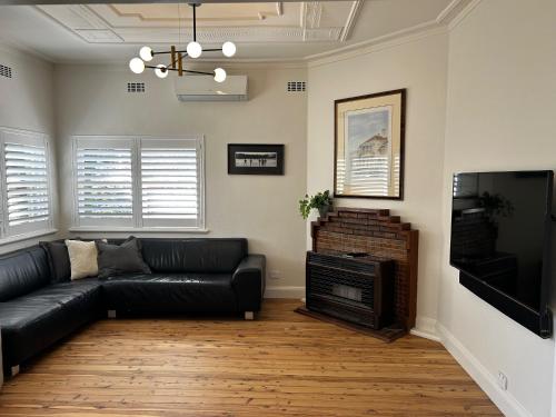 a living room with a black leather couch and a fireplace at Pristine and Private on Pemberton in Albury