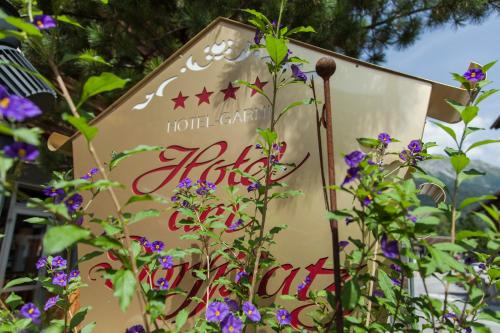 a sign in the middle of some flowers at Am Dorfplatz Suites - Adults friendly in Sankt Anton am Arlberg