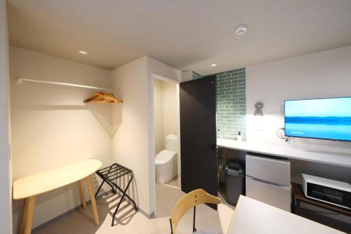 a living room with a desk and a tv on a wall at Grand Pia 2, Bentencho in Osaka