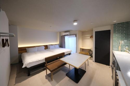 a bedroom with a bed and a table and a kitchen at Grand Pia 2, Bentencho in Osaka