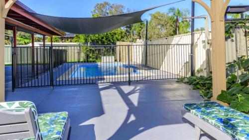 a patio with a fence and a swimming pool at Shelly's Beach House in Bellara