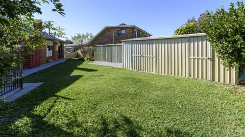 a backyard with a fence and a grass yard at Shelly's Beach House in Bellara