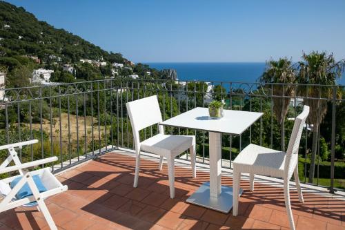 a white table and chairs on a balcony with the ocean at Hotel Syrene in Capri
