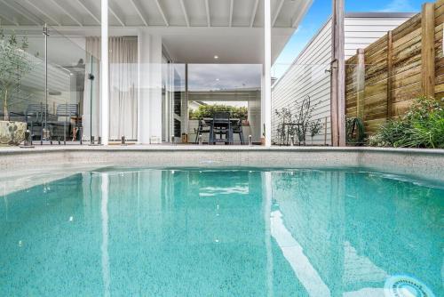 a swimming pool in front of a house at Sanctuary Spaces - Lomani Six in Byron Bay