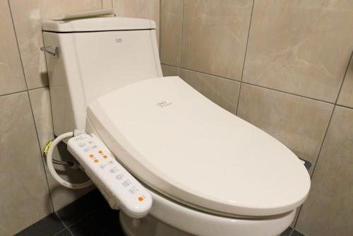 a white toilet in a bathroom with a remote control at Dangjin Dogpelis Glamping in Dangjin