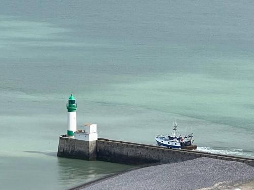 a boat in the water next to a lighthouse at Le Clos D'illies in Mers-les-Bains