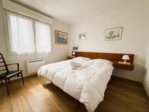 une chambre avec un grand lit blanc et une chaise dans l'établissement Le Clos D'illies, à Mers-les-Bains