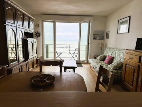 a living room with a table and a couch with a view at Le Clos D'illies in Mers-les-Bains