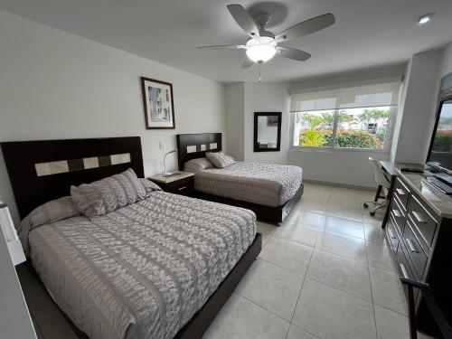 a bedroom with two beds and a desk and a window at Villa Magna departamento en Nuevo Vallarta in Nuevo Vallarta 