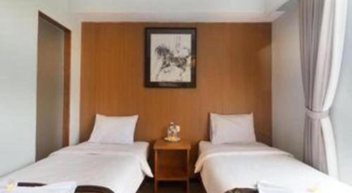 a room with two beds and a picture on the wall at Hadi Poetra Hotel in Kuta