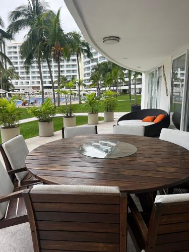 a wooden table and chairs in a patio with palm trees at Villa Magna departamento en Nuevo Vallarta in Nuevo Vallarta
