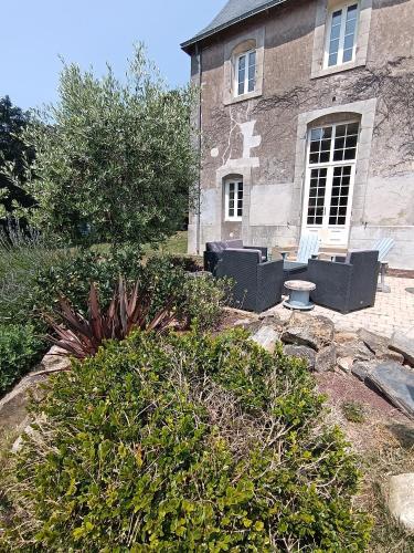 a house with two white benches in front of it at Le Prieuré des Anges in Saint-Quentin-les-Anges