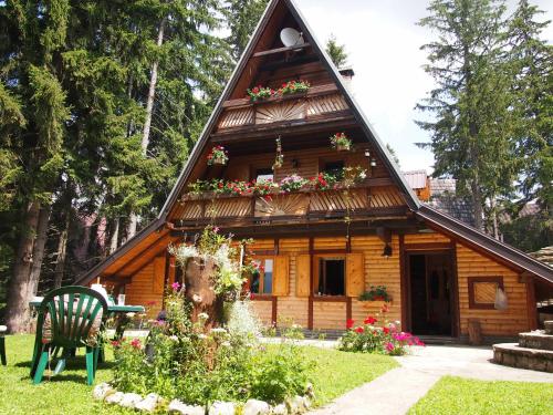 a log cabin with flowers in front of it at Holiday Home Tirol in Vlasic