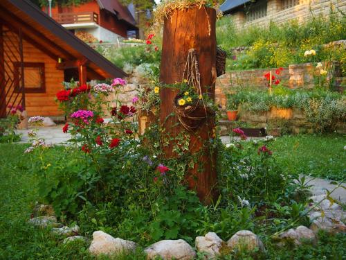 a garden with flowers around a wooden post at Holiday Home Tirol in Vlasic
