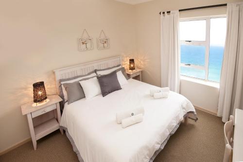 a bedroom with a large white bed with a view of the ocean at Diaz Beach Apartment in Diasstrand