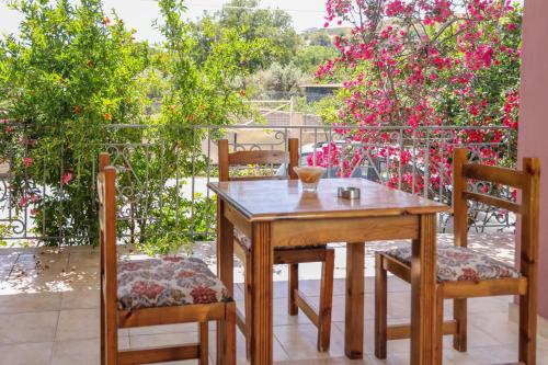 a wooden table and chairs on a balcony with pink flowers at Homely Escape in Chios