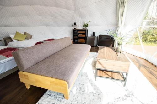 a room with a couch and a bed in a tent at YUKARA Glamping 北海道大沼公園 in Ōnuma
