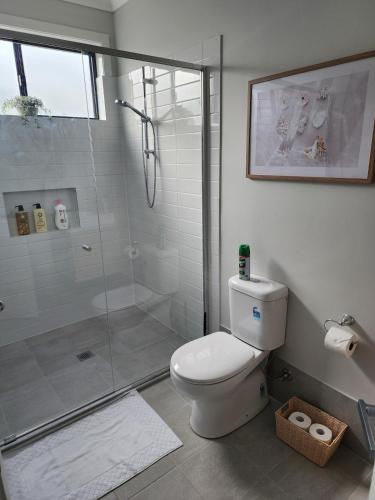 a bathroom with a toilet and a glass shower at The Retreat Modern Cosy Stylish in Holmesville