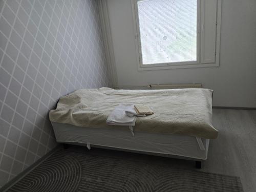 a small bed in a room with a window at Mudita Apartment in Mikkeli