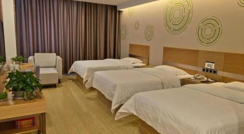 a hotel room with two beds and a chair at GreenTree Inn Ordos Kangbashi District Ulan Mulun Street Branch in Ordos