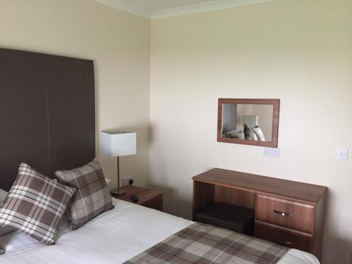 a bedroom with a bed and a desk and a mirror at Bruce's Cottage in Stirling