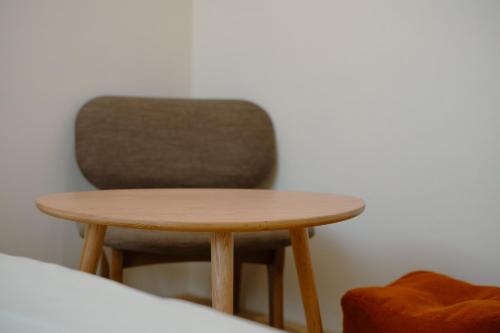 a small wooden table and a chair in a room at Bou house in Tainan