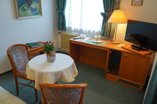 a room with a table and a desk with a television at Pension Besser in Bad Eisenkappel