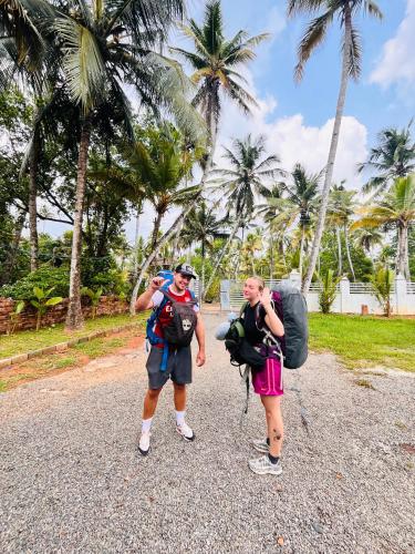 two people standing on a gravel road with palm trees at Riverrootsstays in Munroe Island